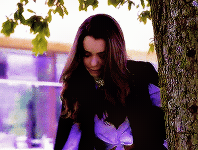 A Woman Leaning Against A Tree Trunk With Her Eyes Closed GIF