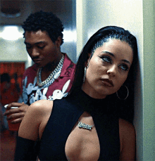 A Woman Leaning Against A Wall With A Man In A Red Shirt Behind Her Smoking GIF