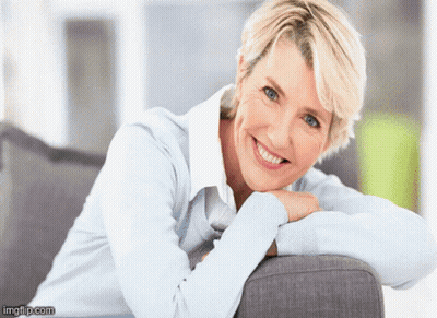 A Woman Leaning On A Couch With Her Head Resting On Her Hand And Smiling GIF