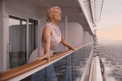 A Woman Leaning On A Railing Looking Out Over The Ocean GIF