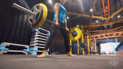 A Woman Lifting A Barbell In A Gym With A Dji Logo On The Floor GIF