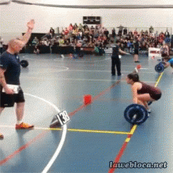 A Woman Lifting A Barbell In A Gym With A Sign That Says 138 GIF