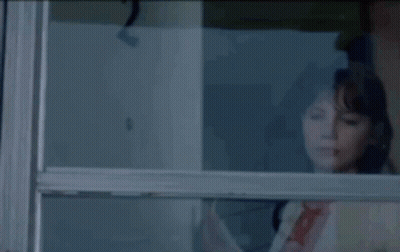 A Woman Looking Out Of A Window With A Reflection Of The Number 2 GIF