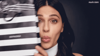 A Woman Making A Face Behind A Black And White Striped Bag GIF