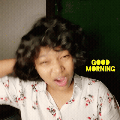 A Woman Making A Funny Face In Front Of A Good Morning Sign GIF