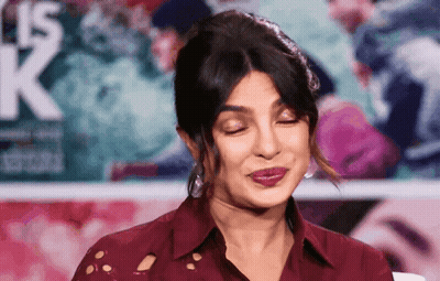 A Woman Making A Funny Face In Front Of A Sign That Says K. GIF