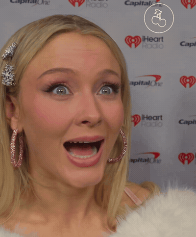 A Woman Making A Funny Face In Front Of A Wall That Says Capital One GIF