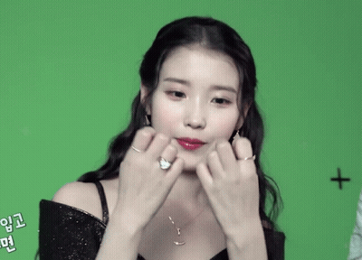 A Woman Making A Heart Shape With Her Hands With A Cross In The Background GIF