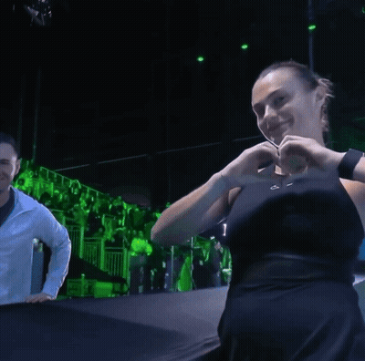 A Woman Making A Heart With Her Hands In A Dark Room GIF