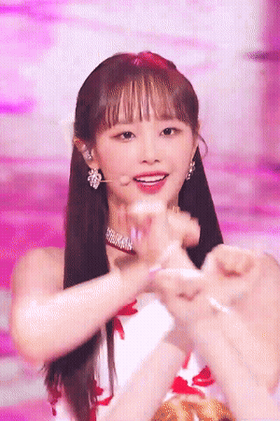A Woman Making A Heart With Her Hands On A Stage GIF