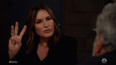 A Woman Making A Peace Sign In Front Of A Man With The Nbc Logo In The Corner GIF