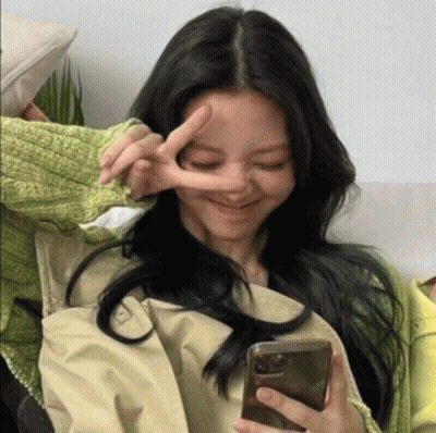 A Woman Making A Peace Sign While Holding A Phone GIF