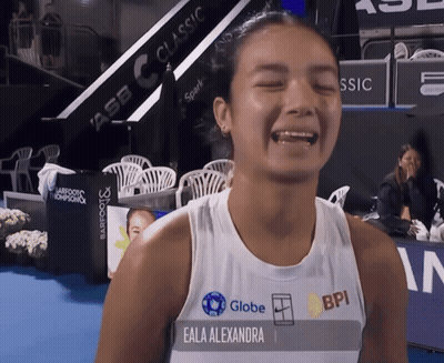 A Woman Named Eala Alexandra Wears A White Tank Top With Globe And Bpi Logos On It GIF
