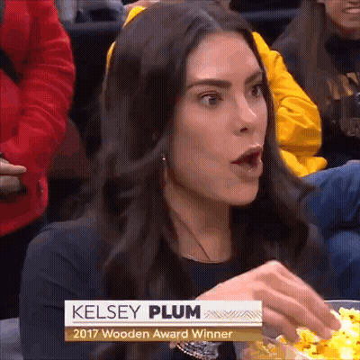 A Woman Named Kelsey Plum Is Sitting In A Crowd Eating Popcorn GIF