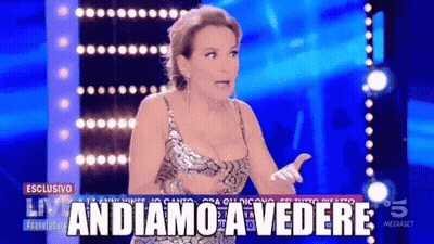 A Woman On A Stage With The Words Andiamo A Vedere On The Screen GIF