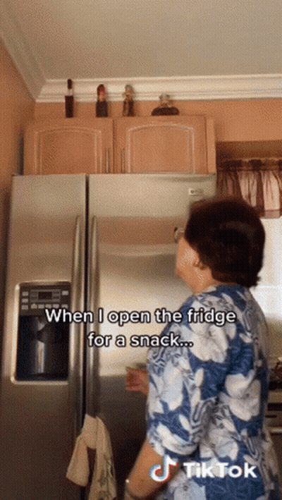 A Woman Opens The Fridge For A Snack With A Tiktok Watermark GIF