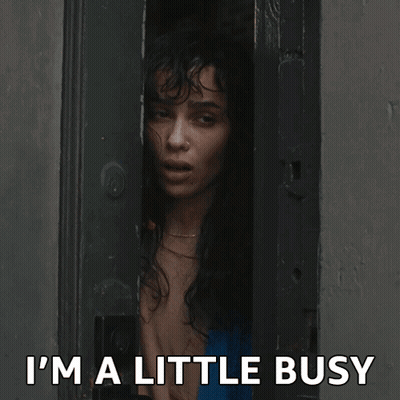 A Woman Peeking Out Of A Door With The Words " I 'M A Little Busy " Above Her GIF