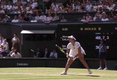 A Woman Playing Tennis In Front Of A Rolex Sign GIF