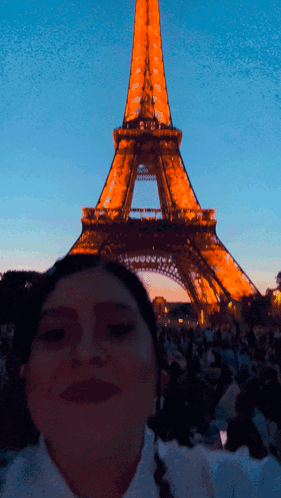 A Woman Poses In Front Of The Eiffel Tower At Night GIF