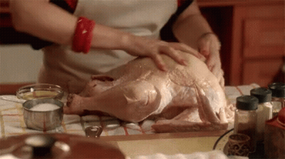 A Woman Prepares A Turkey In A Kitchen GIF