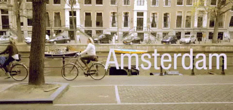 A Woman Riding A Bike Down A Street With The Word Amsterdam Written On It GIF