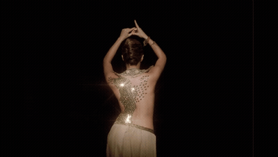 A Woman 'S Back Is Covered In Sequins And Has A Light Shining On Her GIF