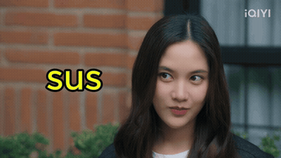 A Woman 'S Face Is Behind A Sign That Says Sus GIF