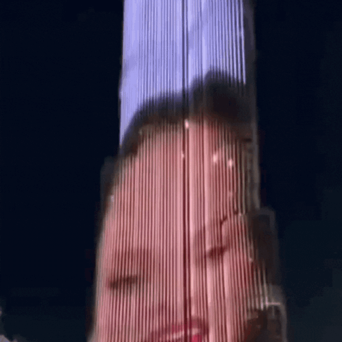 A Woman 'S Face Is Projected Onto A Tall Building At Night GIF