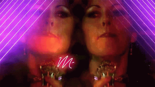 A Woman 'S Face Is Reflected In A Mirror With The Letter M Written In White GIF