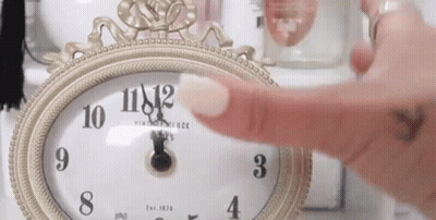 A Woman 'S Finger Is Pointing At A Clock That Shows The Time As 11:42 GIF