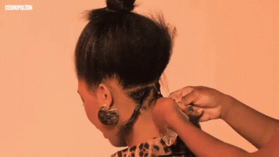 A Woman 'S Hair Is Being Styled In Front Of A Cosmopolitan Ad GIF