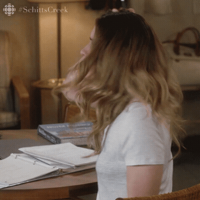 A Woman 'S Hair Is Blowing In The Wind And The Word Schitts Creek Is On The Bottom GIF