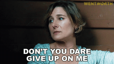 A Woman Says " Do N't You Dare Give Up On Me " In Front Of A Wooden Wall GIF