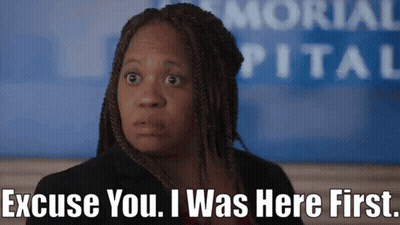 A Woman Says Excuse You I Was Here First In Front Of A Hospital Sign GIF