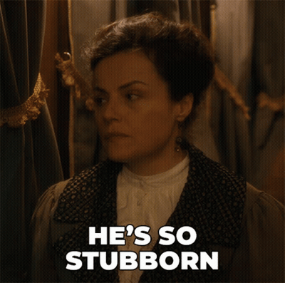 A Woman Says He 'S So Stubborn While Standing In Front Of A Curtain GIF