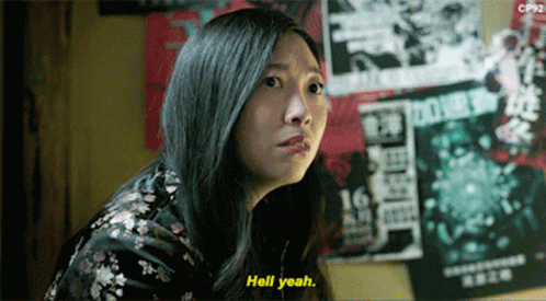 A Woman Says Hell Yeah In Front Of A Wall With Posters On It GIF