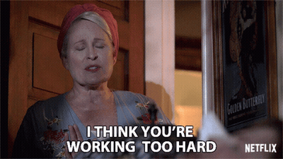 A Woman Says I Think You 'Re Working Too Hard In Front Of A Poster Of The Golden Butterfly GIF