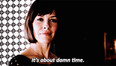 A Woman Says " It 'S About Damn Time " In A Dark Room GIF