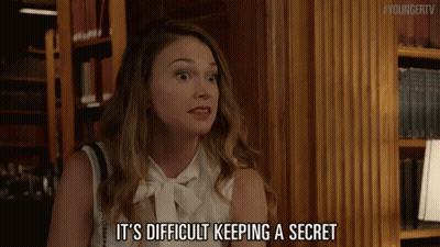 A Woman Says It 'S Difficult Keeping A Secret In Front Of A Bookshelf GIF