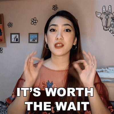 A Woman Says It 'S Worth The Wait In Front Of A Picture Of A Giraffe GIF