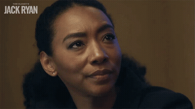 A Woman Says Meaning In Front Of A Jack Ryan Poster GIF