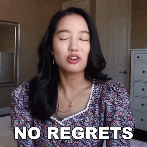 A Woman Says " No Regrets " In Front Of A Mirror GIF