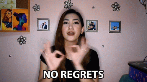 A Woman Says " No Regrets " In Front Of Pictures On A Wall GIF