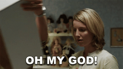 A Woman Says Oh My God In Front Of A Display Of Dolls GIF
