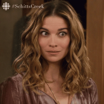 A Woman Says Sorry In Front Of A Picture Of Schitts Creek GIF