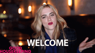 A Woman Says Welcome In Front Of A Good Housekeeping Ad GIF