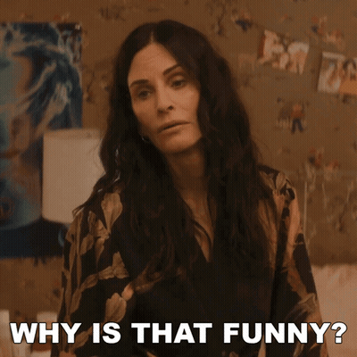 A Woman Says Why Is That Funny In Front Of A Wall Of Pictures GIF