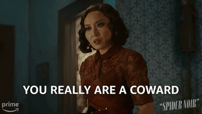 A Woman Says " You Really Are A Coward " In Front Of A Spider Noir Poster GIF