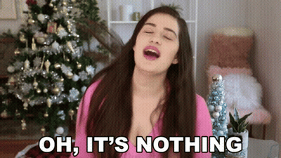 A Woman Singing In Front Of A Christmas Tree With The Words Oh It 'S Nothing Below Her GIF