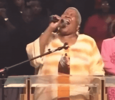 A Woman Singing Into A Microphone At A Podium GIF